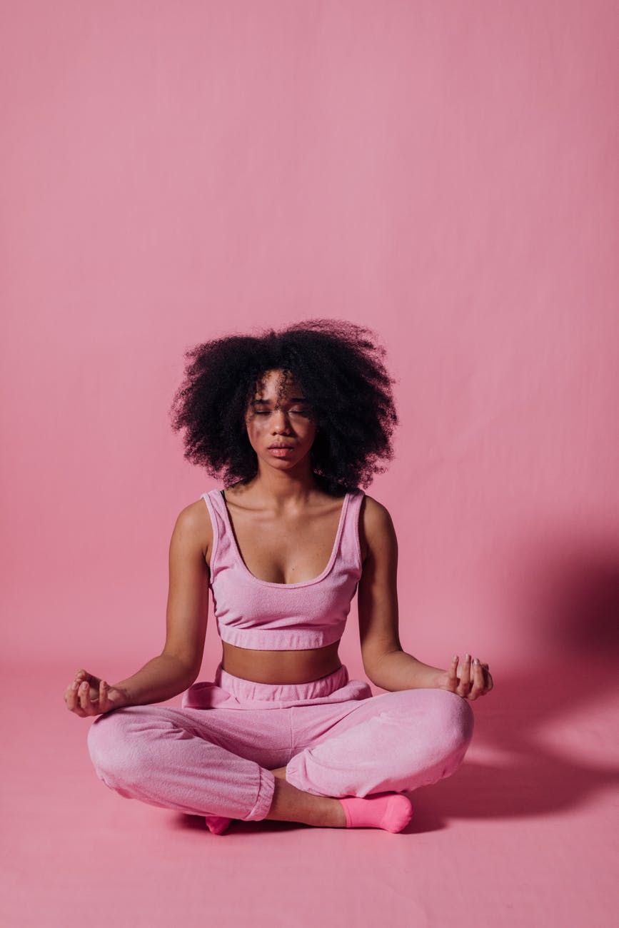 woman in pink crop top and jogging pants practicing yoga